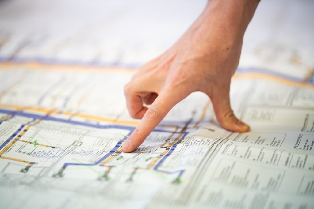 Hand zeigt auf einen Architekturplan mit technischen Zeichnungen