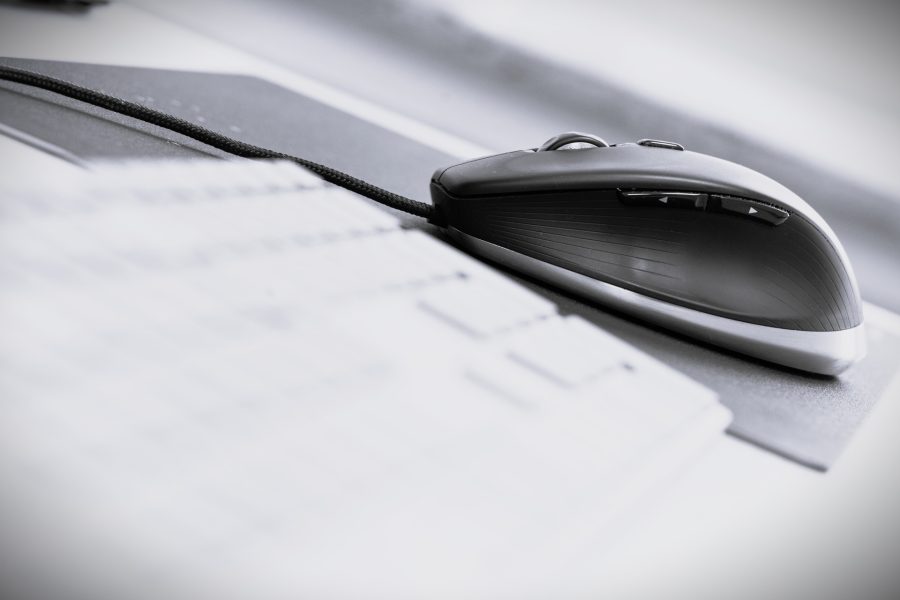 Schwarze Computermaus auf einer Unterlage, mit unscharfem Papier im Vordergrund